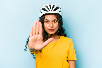 Young hispanic woman wearing a helmet bike isolated on blue background standing with outstretched...