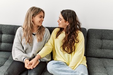 Young couple smiling happy and holding hands sitting on the sofa at home