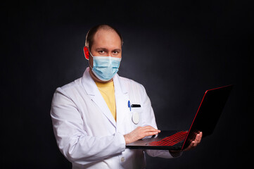young man in a doctor's suit studies a medical history in a laptop - 495464937