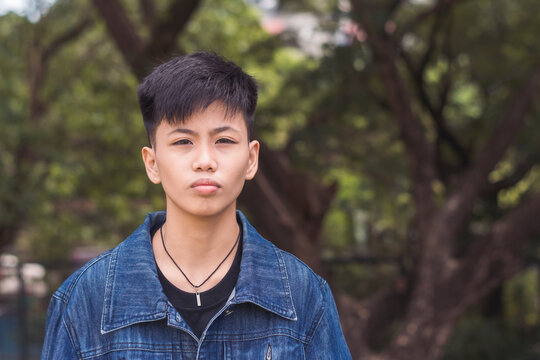A young serious man looking for someone. Focusing his eyes to each people in the location. Feeling bored, annoyed and tired of waiting. Standing outside in the park.