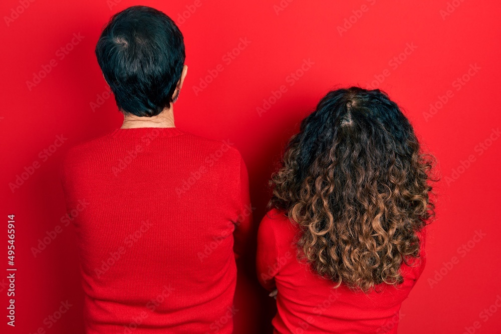 Poster Middle age couple of hispanic woman and man hugging and standing together standing backwards looking away with crossed arms