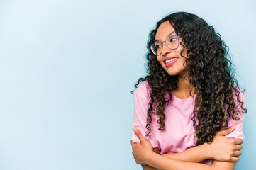 Young hispanic woman isolated on blue background smiling confident with crossed arms.