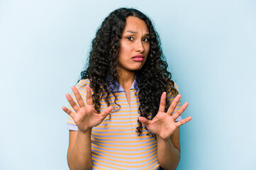 Young hispanic woman isolated on blue background rejecting someone showing a gesture of disgust.