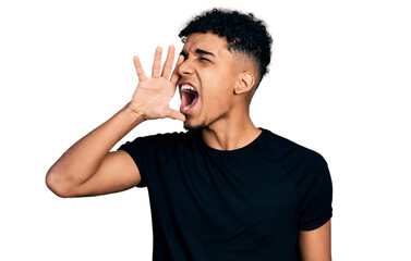 Young african american man wearing casual black t shirt shouting and screaming loud to side with hand on mouth. communication concept.