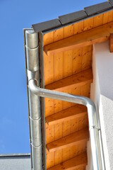 Dachrinne mit Wasserfangkasten und Regenfallrohr aus Zinkblech an einem Neubauhaus