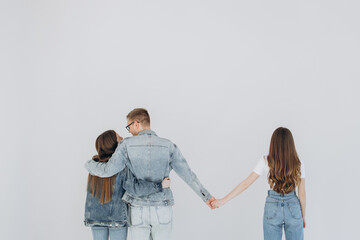 Love triangle. Handsome man embrace his girlfriend while holding hands with another girl. isolated...