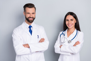 Portrait of two cheerful intelligent surgeon doctors crossed hands isolated on grey color background