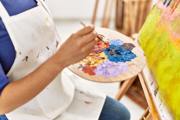 Obraz na płótnie Canvas Young latin woman mixing color on palette at art studio
