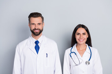 Photo of two positive friendly doctors therapist diagnosis look camera isolated on grey color background