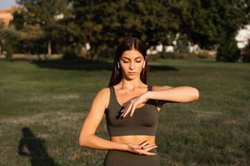 Hand movement of qigong meditation. Attractive girl meditating in the green park. - obrazy, fototapety, plakaty