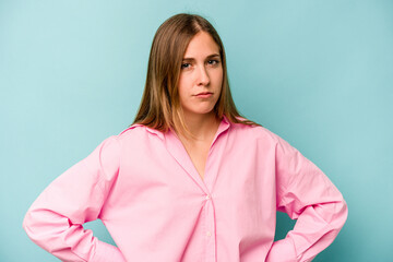 Young caucasian woman isolated on blue background frowning face in displeasure, keeps arms folded.