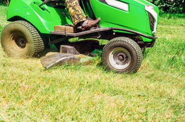 Lawn mower rides on the lawn and mows the grass. Mowing the lawn in the park.