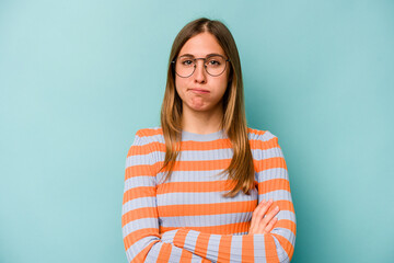 Fototapeta premium Young caucasian woman isolated on blue background blows cheeks, has tired expression. Facial expression concept.