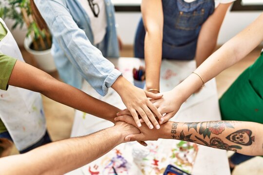 Group of people standing with united hands at art studio.