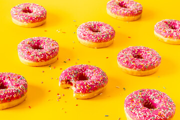 Group of pink frosted donuts with colorful sprinkles