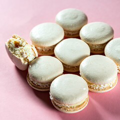 Fresh white macaroons with caramel and coconut on a pink background