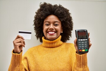 Young african american girl holding credit card  and dataphone at the city.