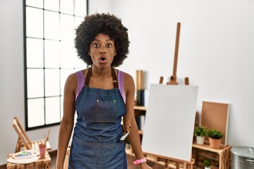 Young african american woman with afro hair at art studio afraid and shocked with surprise and amazed expression, fear and excited face.