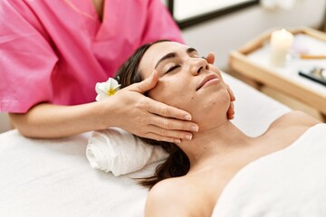 Young hispanic woman smiling confident having massage at beauty center.