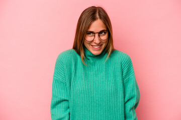 Young caucasian woman isolated on pink background laughs and closes eyes, feels relaxed and happy.