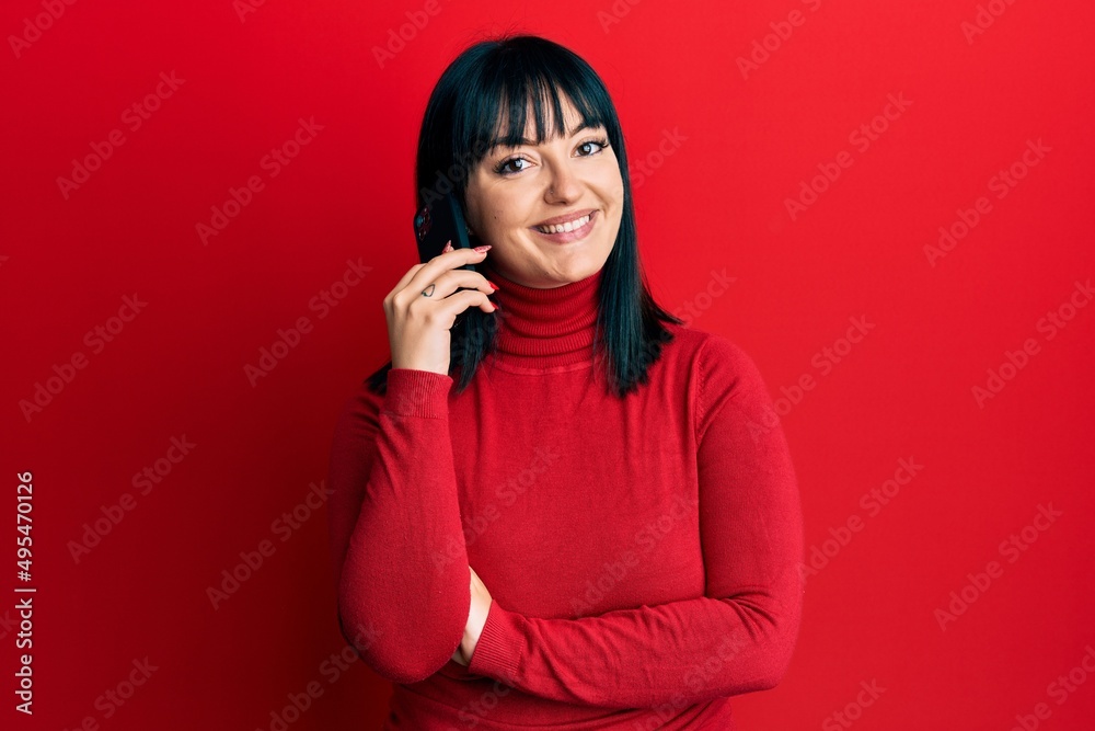 Sticker Young hispanic woman having conversation talking on the smartphone looking positive and happy standing and smiling with a confident smile showing teeth