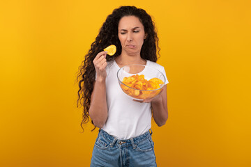 Confused Young Lady Eating Unsavory Potato Crisps