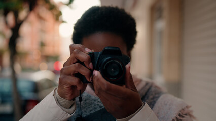 Young african american woman using professional camera at street