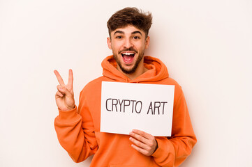 Young hispanic man holding a crypto art placard isolated on white background joyful and carefree showing a peace symbol with fingers.