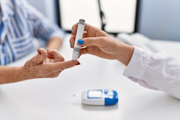 Senior grey-haired woman patient having medical consultation measuring glucose at clinic