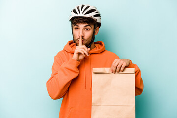 Young hispanic man wearing a helmet bike holding a take away food isolated on blue background keeping a secret or asking for silence.