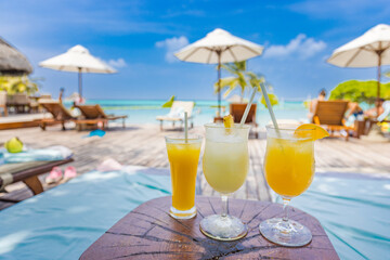 Colorful cocktails on luxury beach resort. Blurred poolside, chairs, beds under umbrella and palm tree leaves. Tropical island beachfront, infinity pool, summer vibes, cool drink glasses