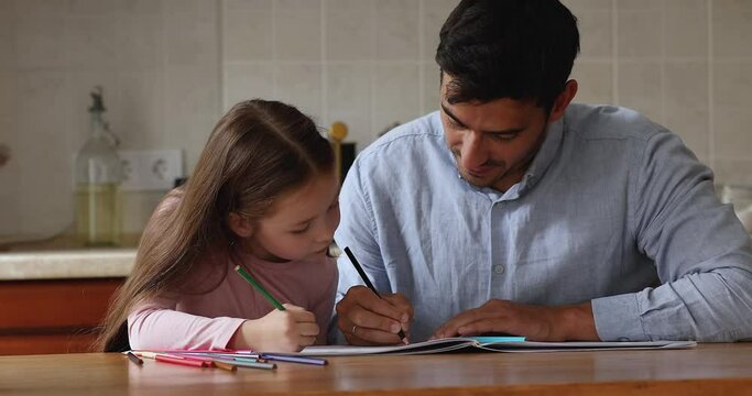Dad teach drawing to his little cute daughter sit in kitchen enjoy hobby, loving parent praises child giving high five looking happy spend time together with favourite pastime. Kid development concept