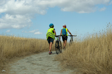 Pienza, Siena-Italy-August 27,2021 Cyclists walking with hand bicycles on the trail