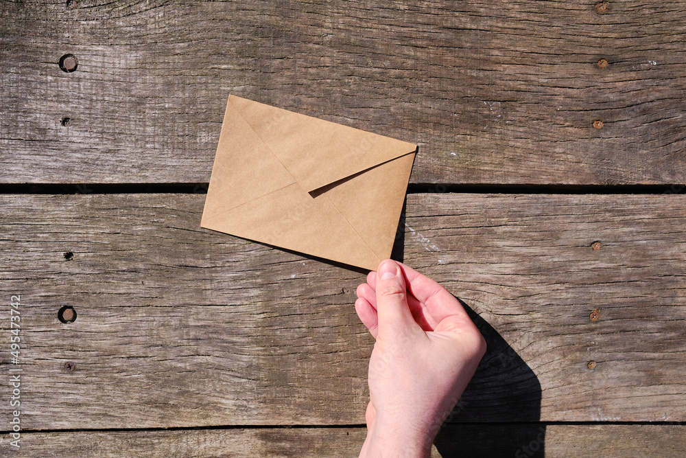 Wall mural a man holds a paper envelope in his hand. new mail, message. postal service. the person wants to sen