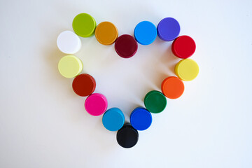 Jars with multi-colored paints in the shape of a heart. Creative background. Paint for drawing. Love postcard. Mock up