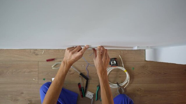 An electrician installs an electric socket outlet into wall. Construction and home repair