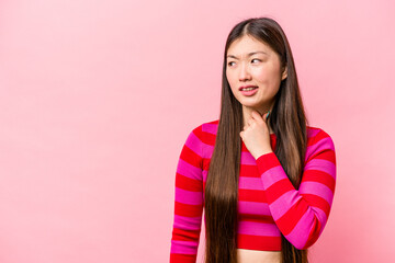 Fototapeta premium Young Chinese woman isolated on pink background touching back of head, thinking and making a choice.