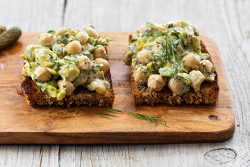 Creamy chickpea salad with avocado, dill, onion and mustard sauce on home made bread