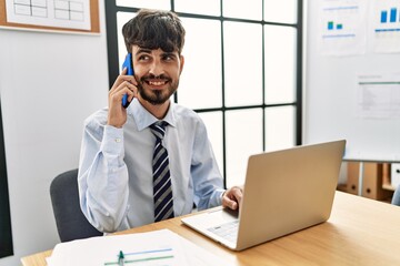 Young hispanic businessman talking on the smartphone working at the office.