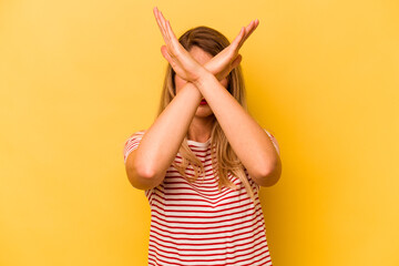 Young caucasian woman isolated on yellow background keeping two arms crossed, denial concept.