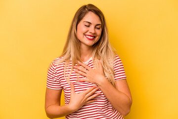 Obraz premium Young caucasian woman isolated on yellow background laughs happily and has fun keeping hands on stomach.