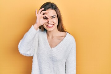 Young caucasian girl wearing casual clothes doing ok gesture with hand smiling, eye looking through fingers with happy face.