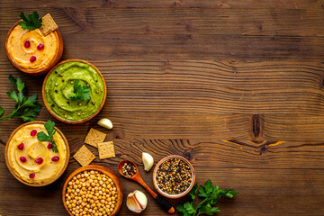 Obraz na płótnie Canvas Flatlay of different types of colorful hummus in bowls. Vegan food background