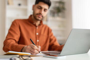 Portrait of focused Arab man using pc and writing