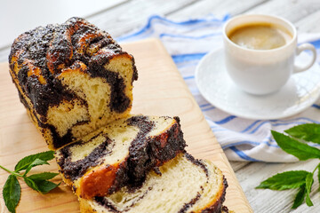 Homemade poppy roll with a cup of coffee on wooden background. Close-up, selective focus