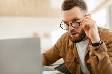 Man Looking At Laptop Screen In Shock Above Glasses Indoor