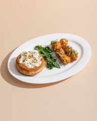 Vegan dinner in restaurant made from mushroom julienne in a bun  and baby potatoes on white plate on beige background