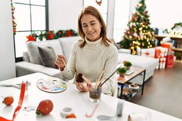 Middle age caucasian woman drawing pineapple to decor christmas tree at home