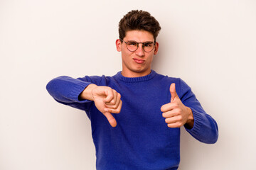 Young caucasian man isolated on white background showing thumbs up and thumbs down, difficult...
