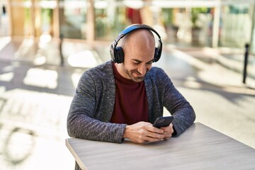 Young man smiling confident listening to music at coffee shop terrace